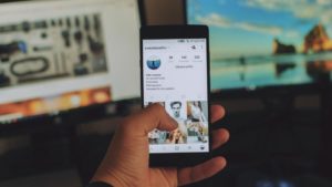 Foto de um homem segurando o celular com o aplicativo aberto, representando as mudanças no instagram em 2019